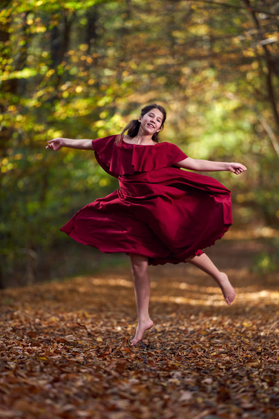 Young teenage girl in red dress dancing in the forest - Valokuva, kuva