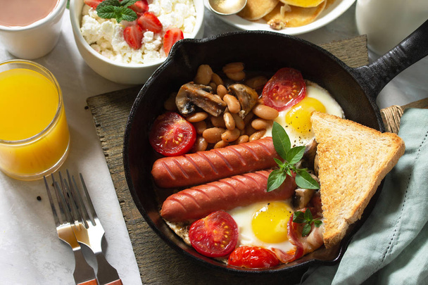 Keto śniadanie: smażone jajka, kiełbaski, fasola, bekon, grzyby, g - Zdjęcie, obraz