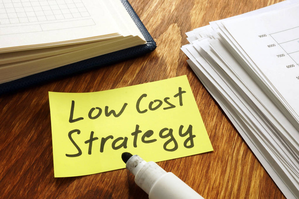 Low cost strategy sign and stack of papers. - Zdjęcie, obraz