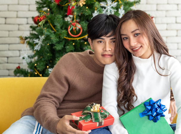 Portrait of couple holding gift box present celebrating Christmas festival holiday in living room with Christmas decoration Ornamental - Fotó, kép