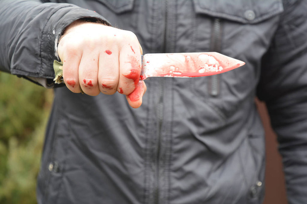 Koncepcja ataku nożem. Morderco, zabójca atakuje nożem czerwone sztuczne krople krwi na zewnątrz.  - Zdjęcie, obraz