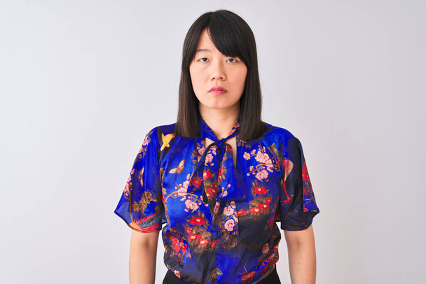 Jovem mulher chinesa bonita vestindo verão floral t-shirt sobre fundo branco isolado Relaxado com expressão séria no rosto. Simples e natural olhando para a câmera
. - Foto, Imagem