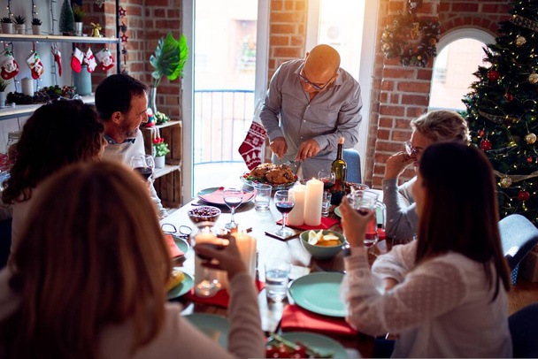 Familia y amigos cenando en casa celebrando la víspera de Navidad con comida tradicional y decoración, preparando pavo para la cena
 - Foto, Imagen