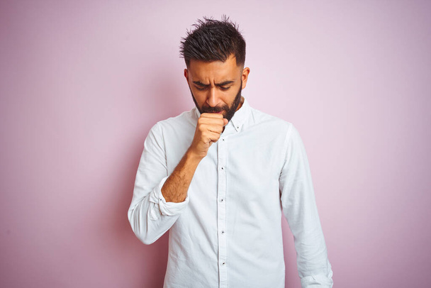 Молодий індійський бізнесмен в елегантній сорочці, що стоїть над ізольованим рожевим тлом, відчуває неприємність і кашель як симптом застуди або бронхіту. Концепція охорони
. - Фото, зображення