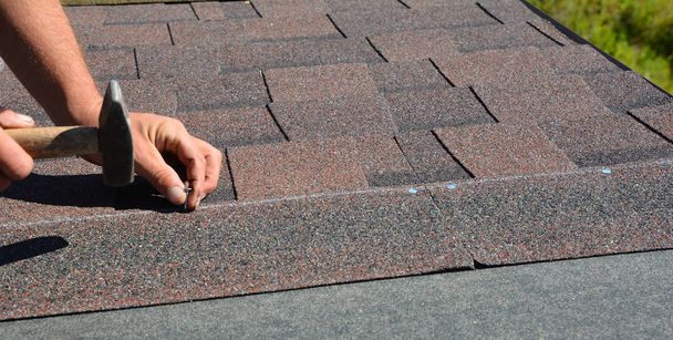 mani Roofer installazione tegole di asfalto su casa angolo tetto di costruzione con martello e chiodi. Foto Panorama Costruzione Coperture
.  - Foto, immagini