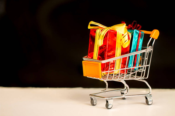 Online shopping concept - trolley kar vol met cadeautjes. - Foto, afbeelding