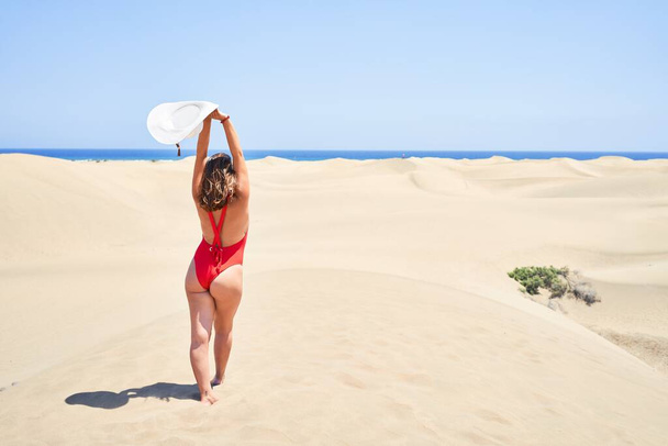 Young beautiful woman sunbathing with open arms wearing summer swinsuit at maspalomas dunes bech - Foto, afbeelding