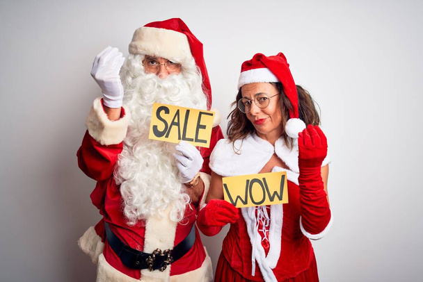 Pari yllään Santa puku tilalla wow ja myynti banneri yli eristetty valkoinen tausta tekee Italian ele käsin ja sormin luottavainen ilme
 - Valokuva, kuva