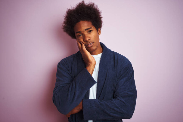 Молодий афроамериканець у піжамі стоїть над ізольованим рожевим фоном і виглядає втомленим і нудним через проблеми з депресією з перехрещеними руками.. - Фото, зображення