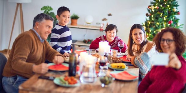 Hermosa familia sonriendo feliz y confiada. Comer pavo asado hacer selfie por teléfono inteligente celebrando la Navidad en casa
 - Foto, imagen