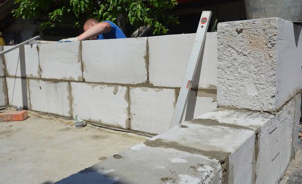 Кирпичный строитель кладет автоклавные газобетонные блоки для стен домов
. - Фото, изображение