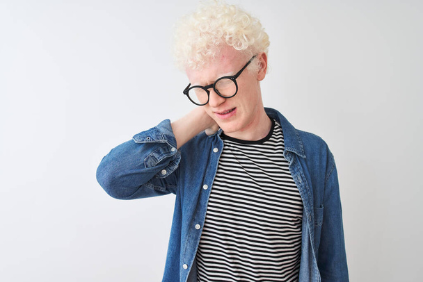 Молодой белокурый альбинос в джинсовой рубашке и очках на изолированном белом фоне с травмой шеи, прикосновение к шее рукой, мышечная боль
 - Фото, изображение