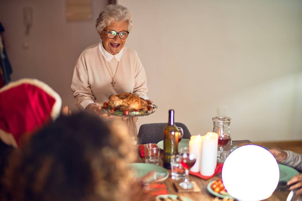 Beautiful group of women smiling happy and confident. Showing roasted turkey celebrating christmas at home - Photo, Image