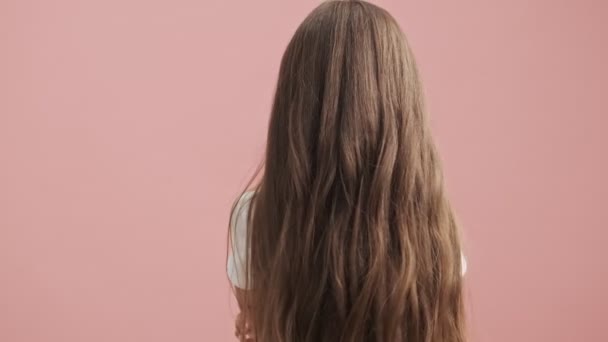 Unhappy little girl is turning around looking down over pink background isolated - Filmagem, Vídeo
