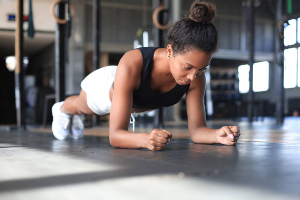 Portrait of a muscular woman on a plank position. - Фото, зображення