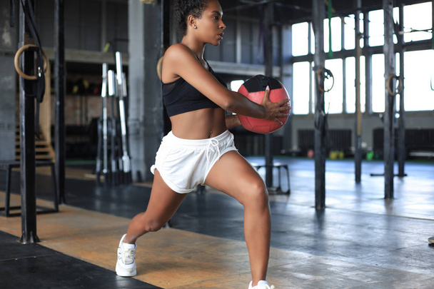 Fit and muscular woman exercising with medicine ball at gym. - Foto, afbeelding