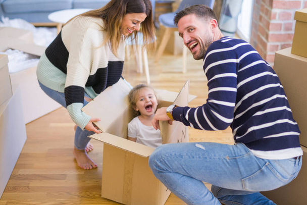 Ребенок, играющий с родителями на картонном ящике в новом доме
 - Фото, изображение
