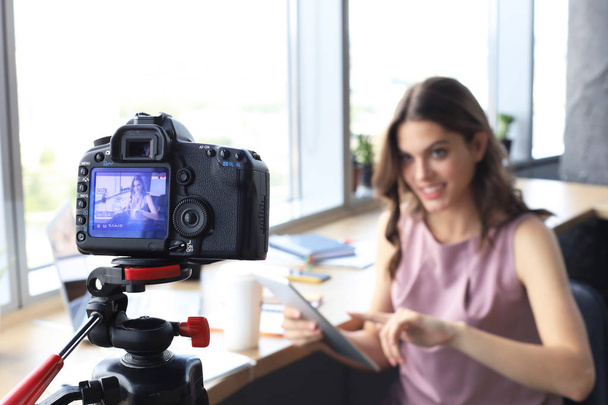 Beautiful young woman talking and smiling while making new video for her blog. - 写真・画像