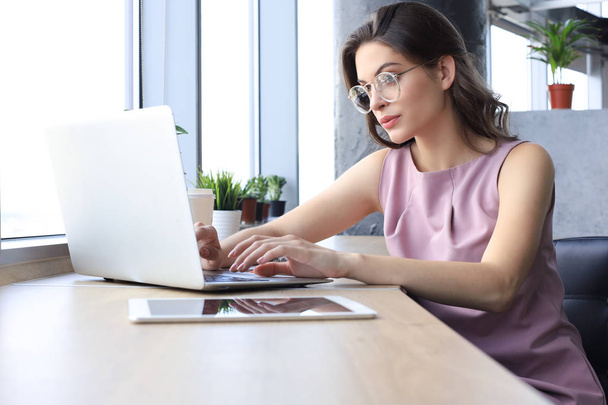 Beautiful business woman in smart casual wear working on laptop in the office - Фото, зображення