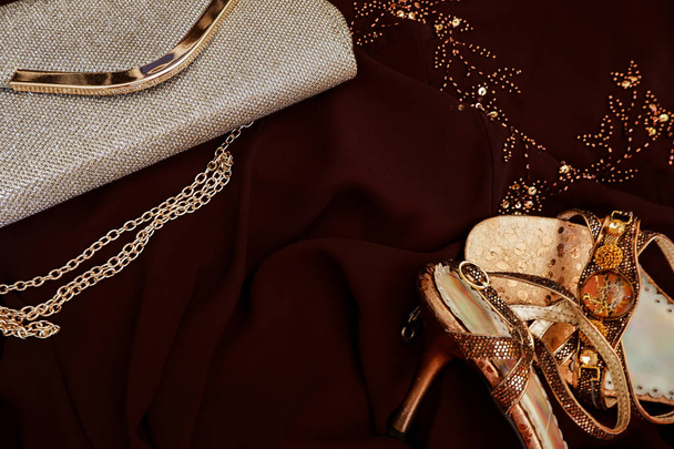 Puesta plana de moda. Ropa formal de noche: vestido marrón, bolso de cadena dorada, tacones altos
 - Foto, Imagen