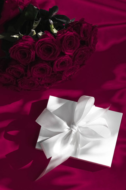 Luxury holiday silk gift box and bouquet of roses on wine backgr - Foto, Imagen