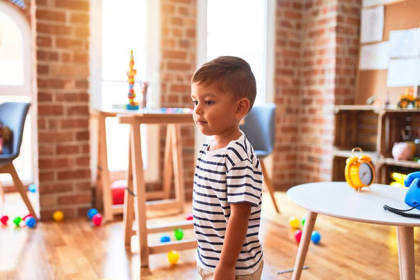Beautiful toddler boy standing at kindergarten with lots of toys - Fotoğraf, Görsel
