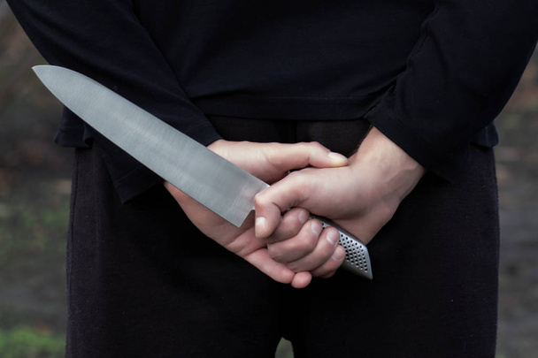 hand with a knife behind his back - Φωτογραφία, εικόνα