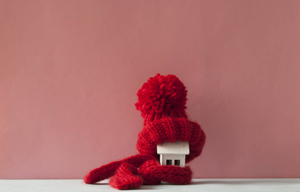 Закрыть концептуальную миниатюрную модель дома красным шерстяным шарфом, ч
 - Фото, изображение
