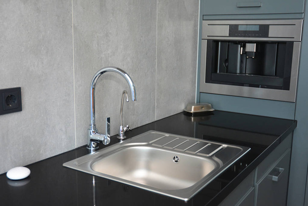 Modern kitchen  with chrome faucet, water tap, black kitchen table, coffee mashine and  kitchen sink. - Photo, Image