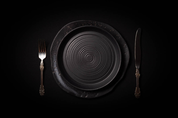 Gros plan 2 assiettes rondes vides en céramique vieilli noir, couverts vintage
 - Photo, image