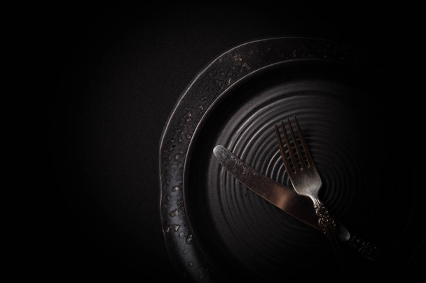 Closeup 2 empty round black aged ceramic plates, vintage cutlery - Photo, Image