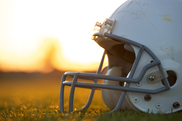 American Football Helmet on the Field at Sunset - Fotoğraf, Görsel
