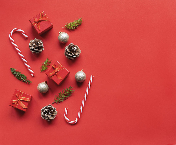 Christmas composition, on a red background Christmas golden balls , fir tree  , gift boxes and candy canes . Flat lay, top view, copy space , place for text.  - Photo, Image