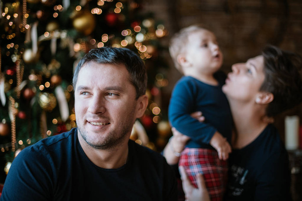 Portret taty na tle mamy z dzieckiem w domu przy drzewie noworocznym.  - Zdjęcie, obraz