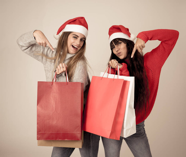 Excited teenagers with shopping bags buying christmas gifts on black friday or sales wearing a santa hat. Paper bags with copy space for text. People, Fashion, Christmas shopping and shop addiction. - Fotoğraf, Görsel