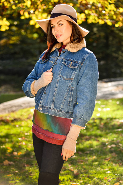 Fashionable young woman in autumn park. Warm sunny weather. Fall concept - 写真・画像