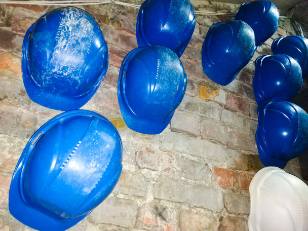 сині будівельні шоломи на цегляній стіні
 - Фото, зображення