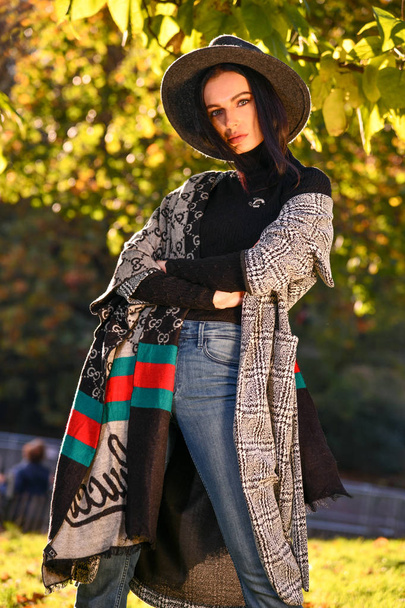 Outdoor fashion photo of young beautiful lady in autumn park on sunny day.  - Fotó, kép