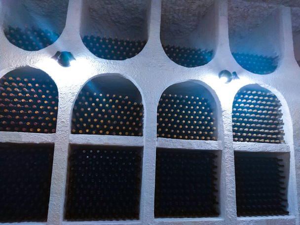 Dusty wine bottles on shelfs in cellars of winery - Valokuva, kuva