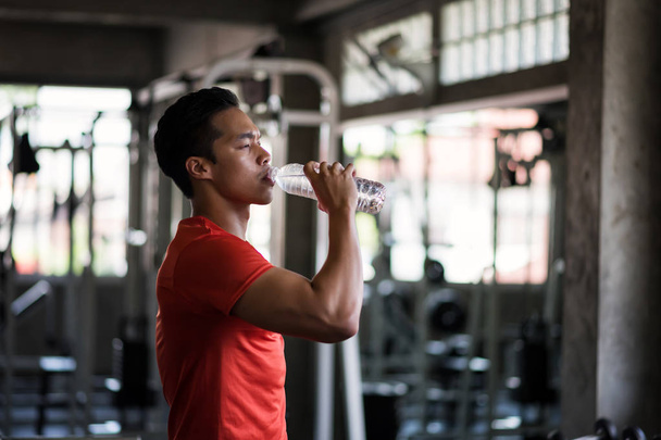 Stanco fitness uomo bere acqua in palestra
 - Foto, immagini