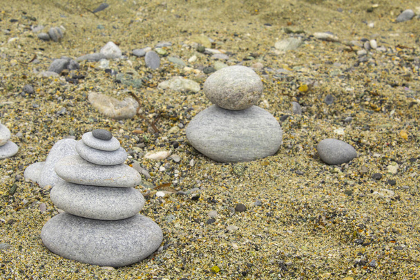 pierre zen sur sable, galets d'art, petites pierres plates soigneusement placées ensemble, conceptuellement, pour ressembler à une forme pyramidale
 - Photo, image