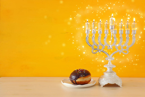 religion image of jewish holiday Hanukkah background with menorah (traditional candelabra) and doughnut - Photo, Image