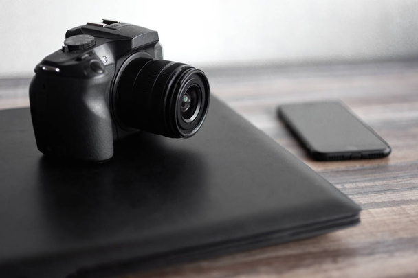 Фотограф или концепция стоковой фотографии, цифровая черная камера рядом с ноутбуком и телефоном на настольной рабочей станции
 - Фото, изображение
