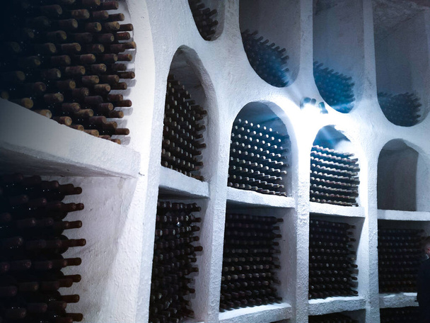Staubige Weinflaschen auf Regalen in Kellern von Weingut - Foto, Bild