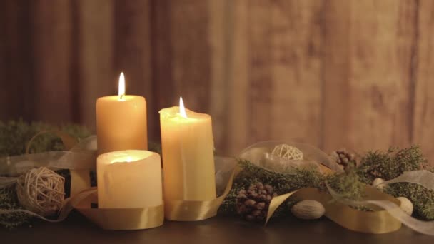 3つのライト付きキャンドル、松の枝、天然松のコーン、黄金のサテンと白のオーガニックリボンの装飾の移動炎とクリスマスの設定 - 映像、動画