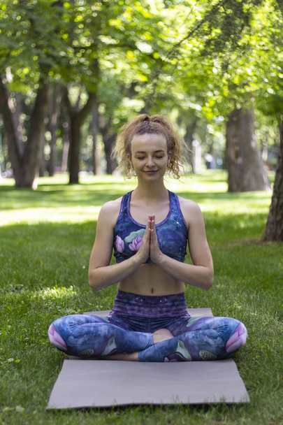 Girl with curly blond hair practices yoga in the park. - Foto, imagen