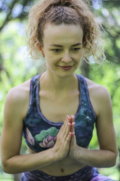 Девушка с вьющимися светлыми волосами практикует йогу в парке
. - Фото, изображение