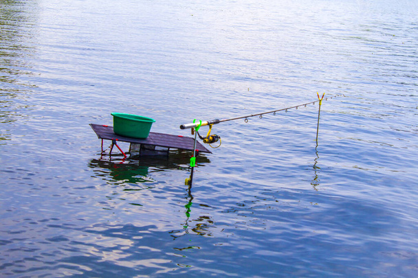 Pesca com haste de pesca alimentador no rio, vista do lugar do pescador durante a pesca. Vara de pesca na água sem homem. Lago e água parada
 - Foto, Imagem