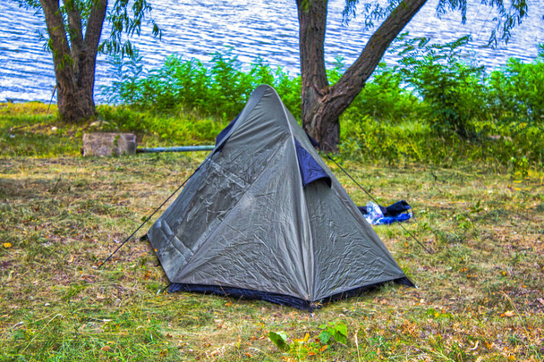 natura krajobraz namiot kemping pod drzewem na zielonej trawie łąka lub park z jeziorem lub rzeką na piknik podróży na rodzinne wakacje i wakacje relaks - Zdjęcie, obraz