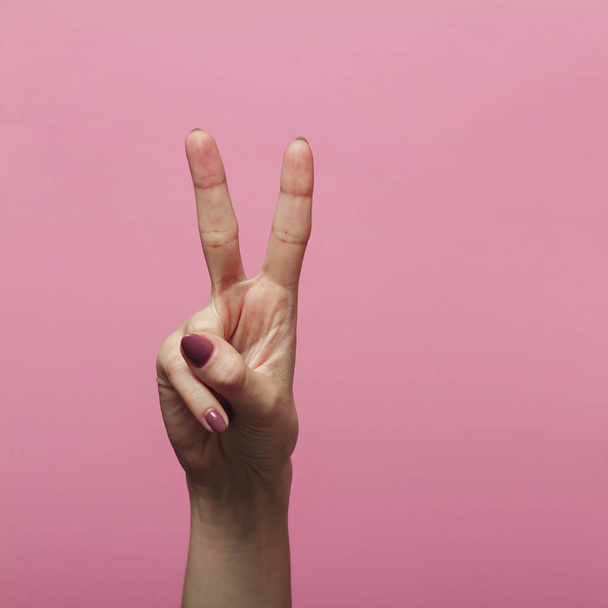 női kéz mutatja a második a dátum az új év 2020, jelnyelv a színes rózsaszín háttér - Fotó, kép